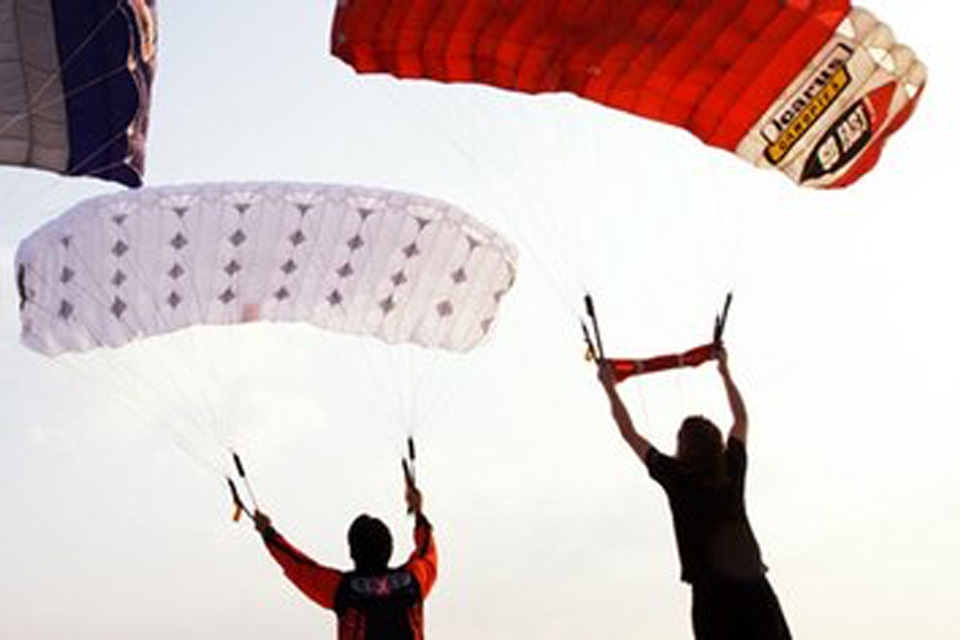 Skydivers under white and red canopies