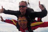 Tandem skydiving instructor gives thumbs up with student in freefall