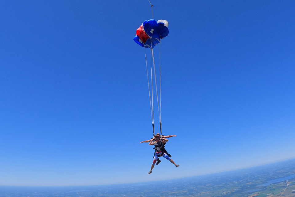 tandem canopy opening at wisconsin skydiving center with beautiful blue sky behind