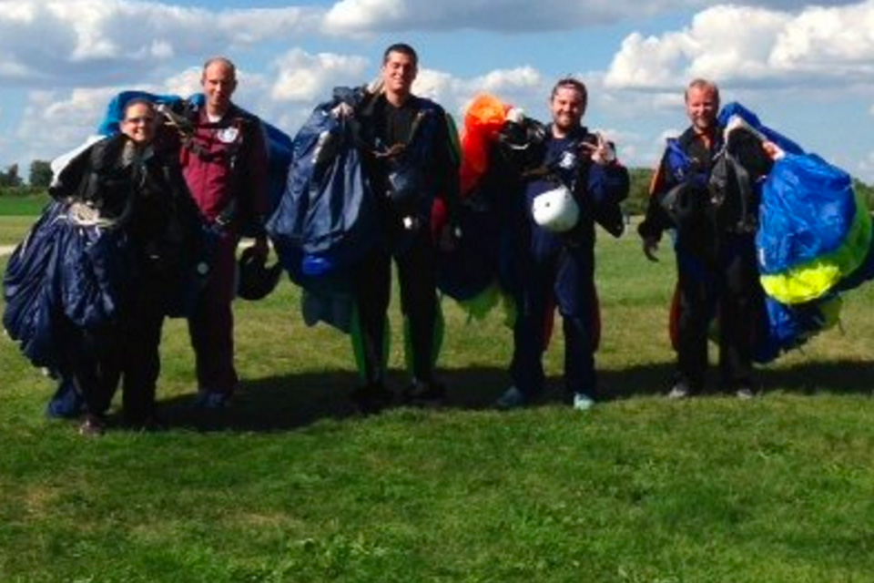 Group of skydivers after landing from a jump holding their canopies
