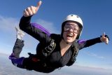A licensed skydiver gives to thumbs up while flying on her belly in freefall