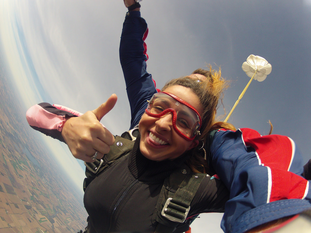 Woman in cute outfit smiling and giving a thumbs up in skydiving freefall at Wisconsin Skydiving Center near Milwaukee