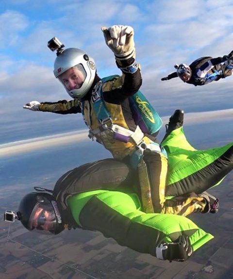 Skydiving instructor Laura Duffy riding a fellow wingsuit skydiver