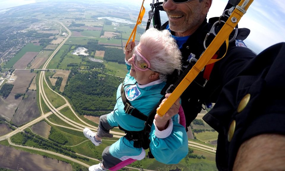 Anna Mae smiles while flying under parachute with tandem instructor, Bo