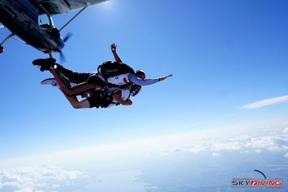 A tandem instructor and his student arch as they leave the plane.