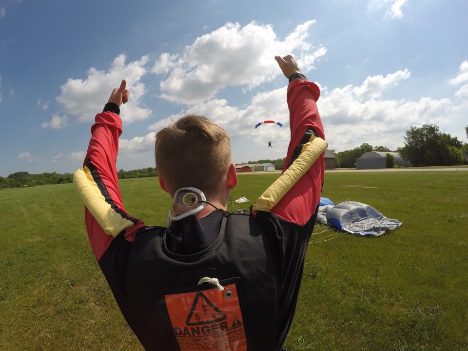 Man finishing a skydive and cheering on his friend as she lands at Wisconsin Skydiving Center near Milwaukee