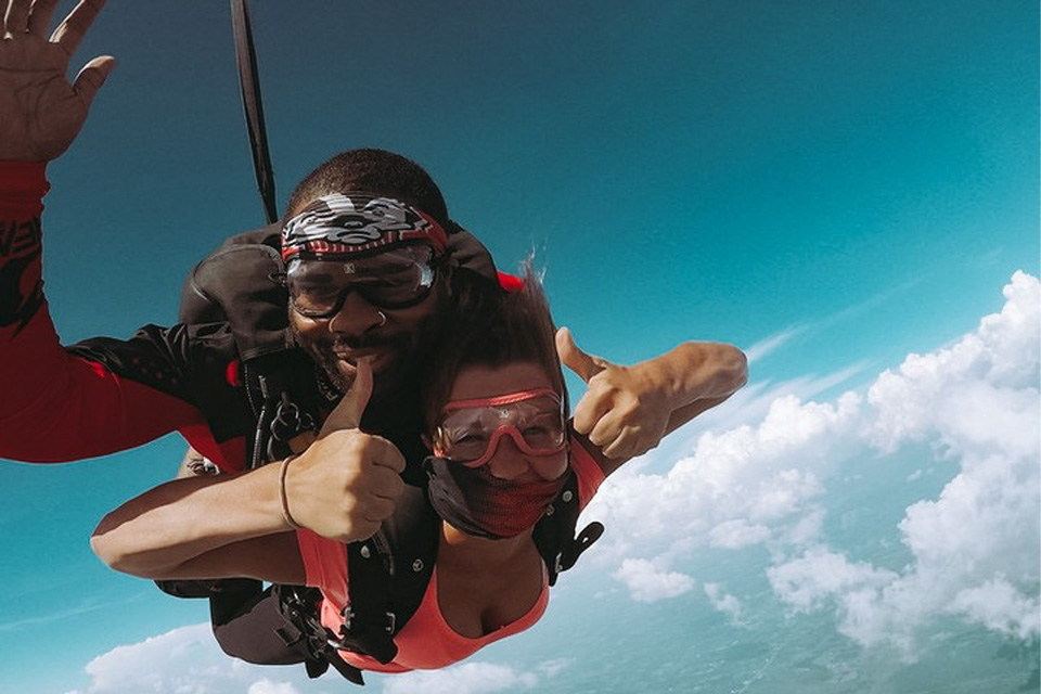 Woman in cute skydiving outfit giving thumbs up during a tandem skydive at Wisconsin Skydiving Center
