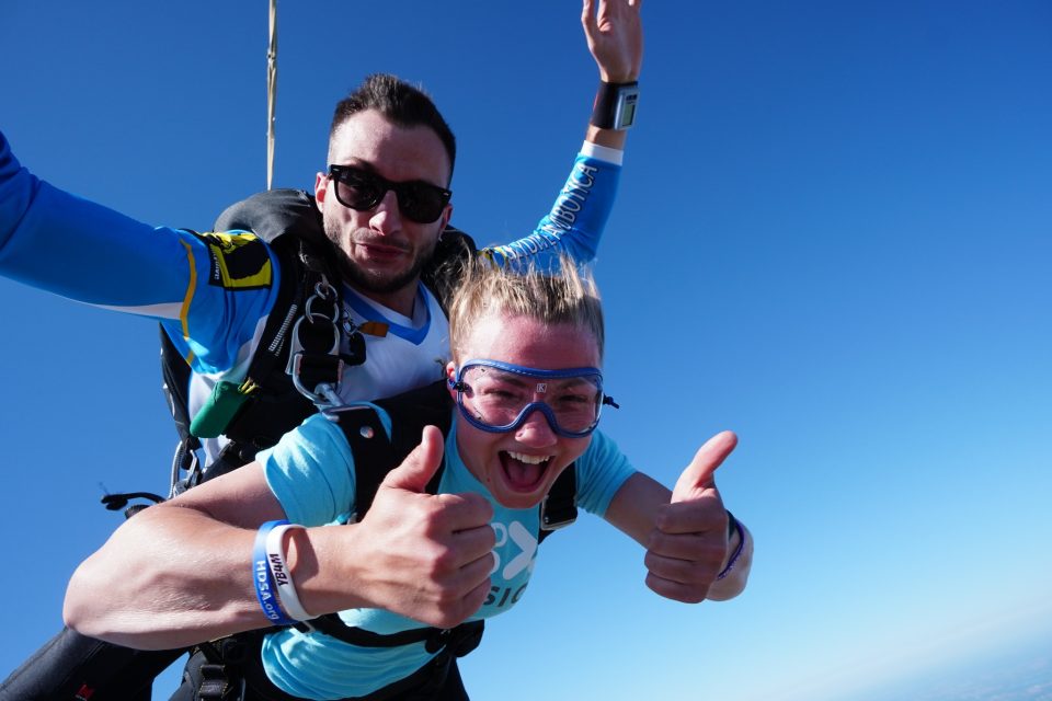 Woman giving thumbs up during tandem freefall after her first skydive at Wisconsin Skydiving Center