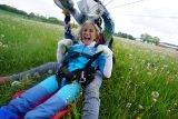 Woman smiling and touching her harness after landing from a tandem skydive