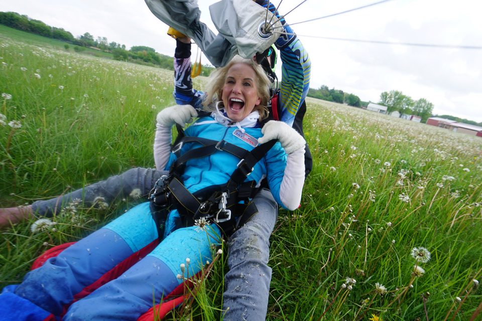 Woman smiling and touching her harness after landing from a tandem skydive