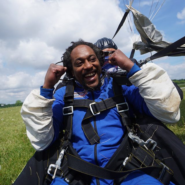 Man smiles and pumps fists after landing from a tandem skydive
