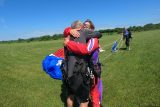 Tandem skydiving passengers hug after landing