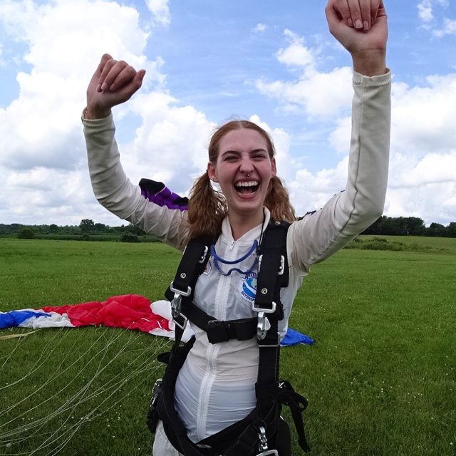 Young female excited with her hands in the air after landing from a skydive