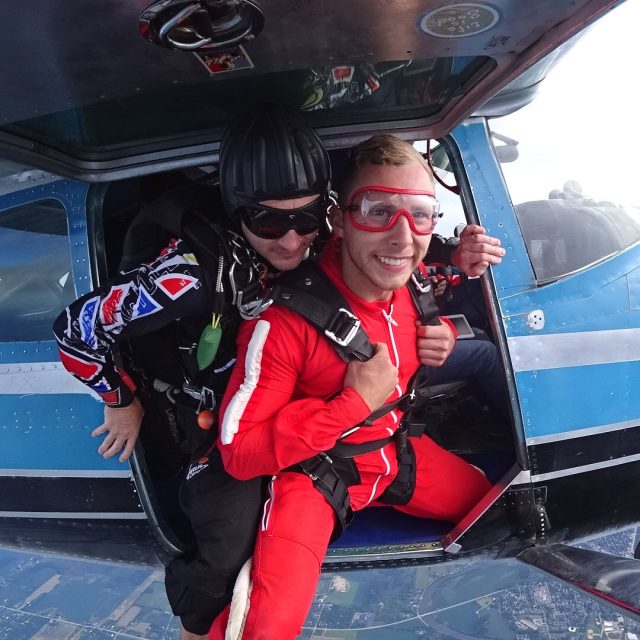 Male tandem skydiving pair prepare to exit the airplane together