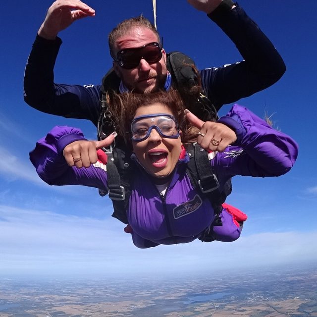 Female tandem students gives two thumbs up during freefall