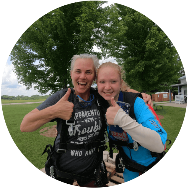 Two female tandem skydivers give a thumbs up