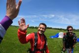 Tandem skydiver gives a high five after landing