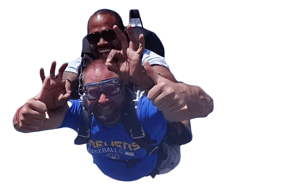 Cutout image of a male tandem student giving a thumbs up and his instructor giving the "OK" hand signal during freefall.