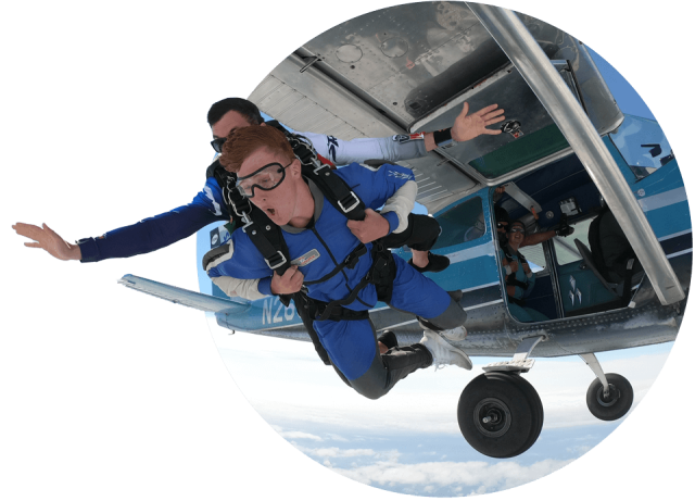 Tandem instructor and student in a blue jumpsuit exit the airplane.