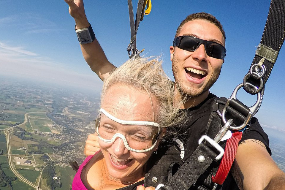 blonde tandem woman smiling under canopy on tandem skydive