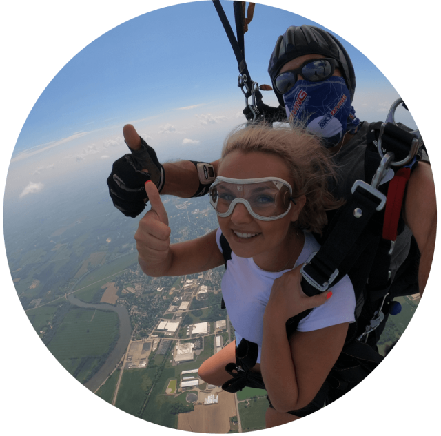 Tandem student and her instructor give a thumbs up under canopy