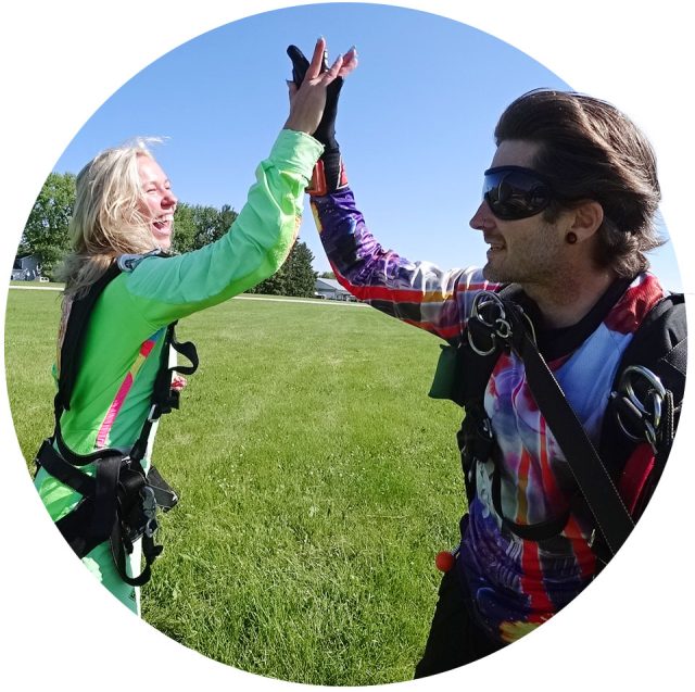 Tandem instructor and his student high five on the ground after landing from a skydive near Milwaukee.
