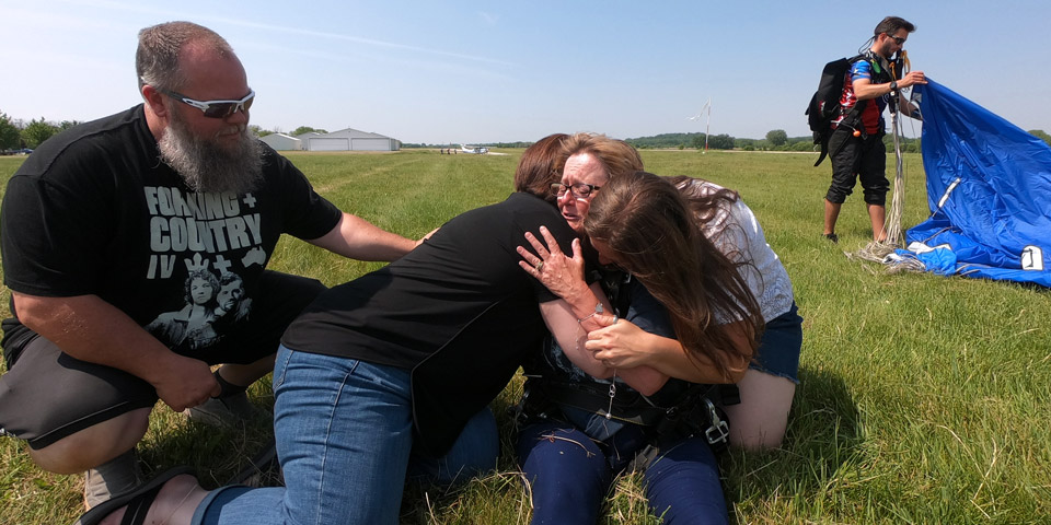 Barb hugging her family after landing from a tandem skydive.
