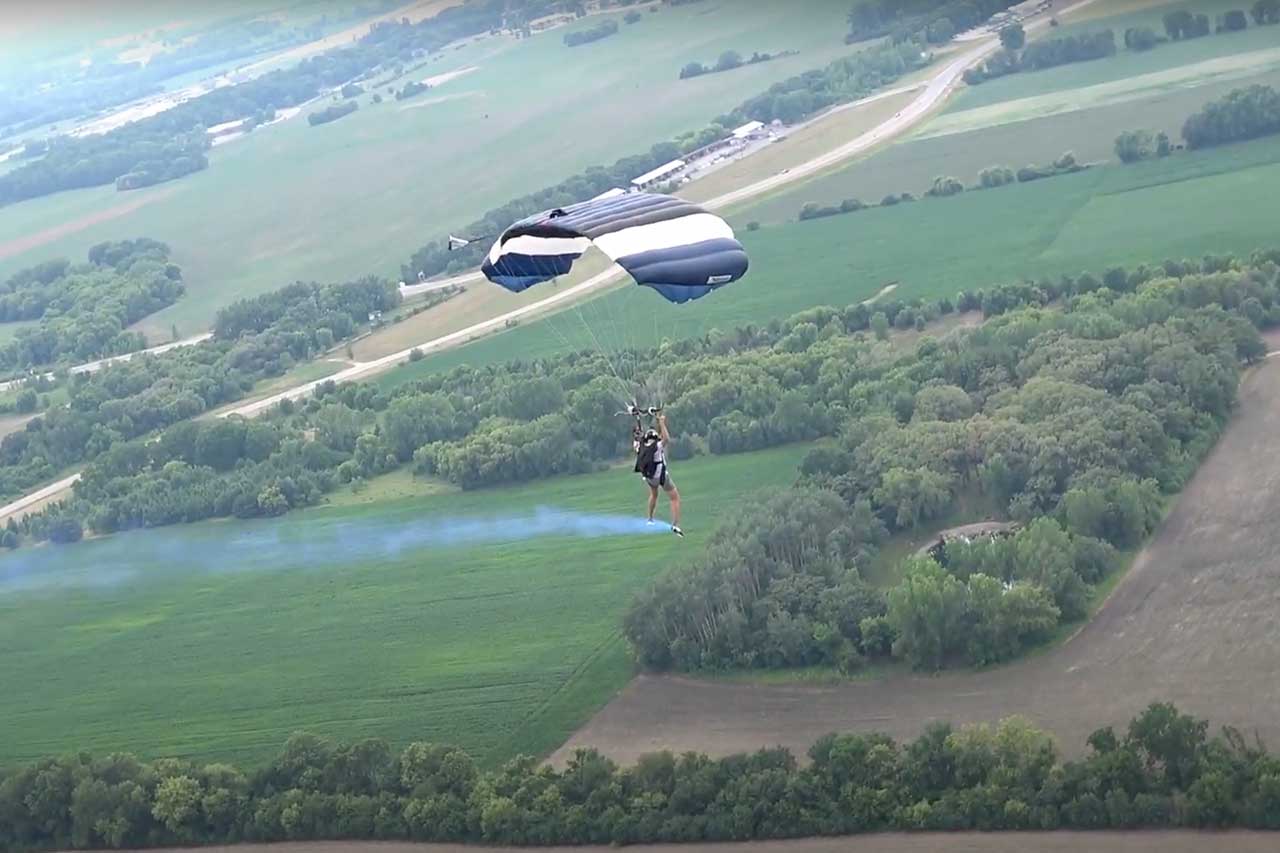 Skydiver with blue smoke canister reveals baby boy's gender.