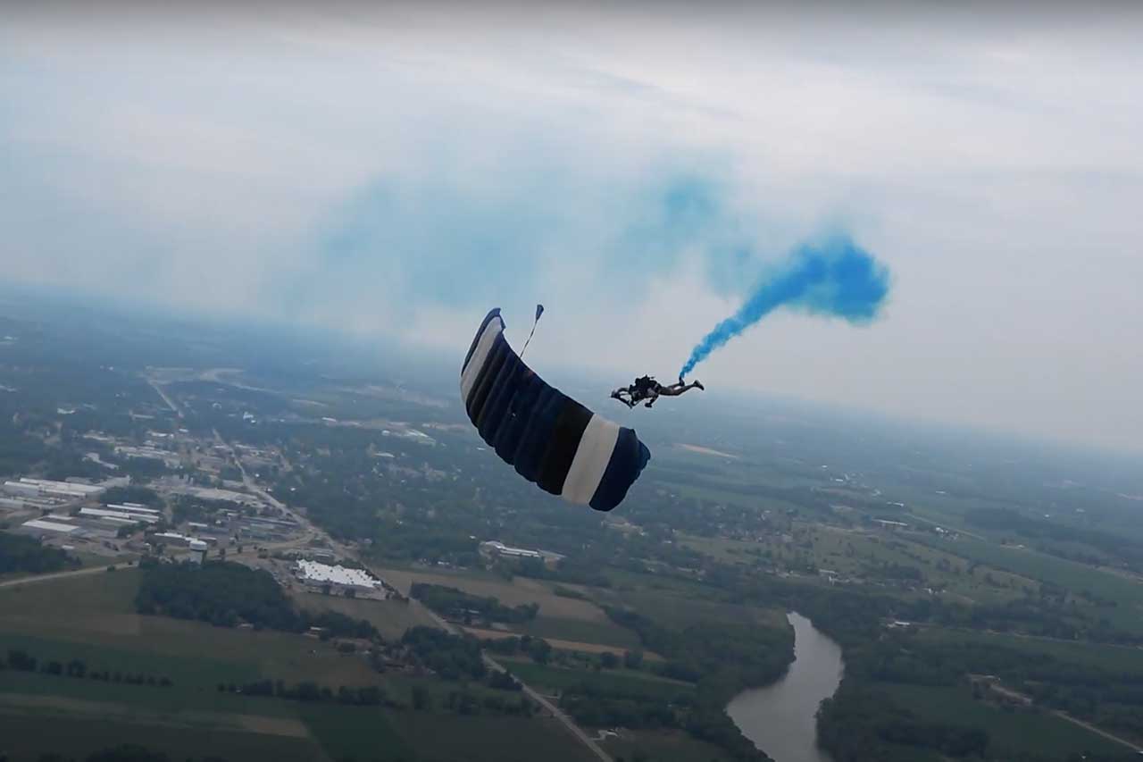 Skydiver with blue smoke canister reveals baby boy's gender.