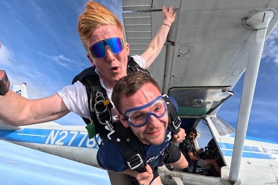 Two male tandem skydivers exit Cessna aircraft for a skydive