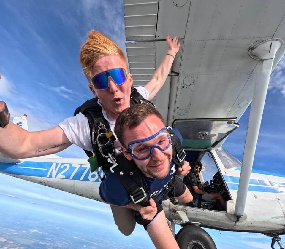 Two male tandem skydivers exit Cessna aircraft for a skydive