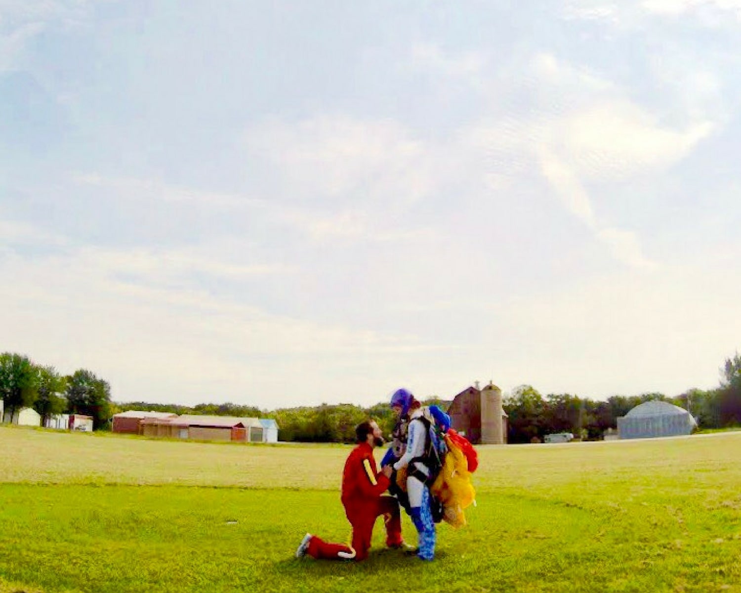 male skydiver kneels to propose to female skydiver